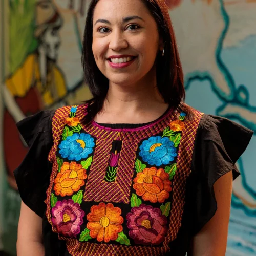 Lifestyle portrait of woman wearing traditional embroidered top.