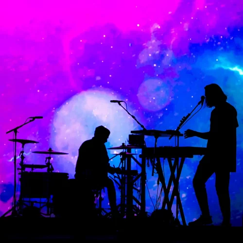 Electronic music performer on stage with purple haze and a starry background.