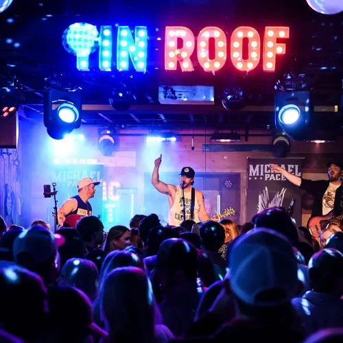 Crowd at Tin Roof concert captured under blue lights in Raleigh, North Carolina.