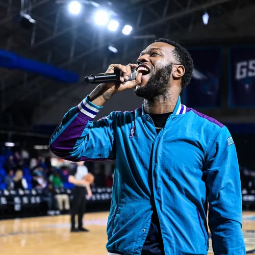 Performer singing on basketball court during halftime show of the Greensboro Swarm.