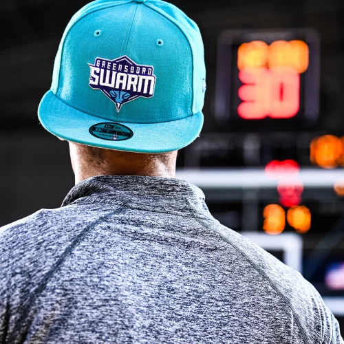 Man wearing branded hat during a Greensboro Swarm and Charlotte Hornets merchandise shoot.