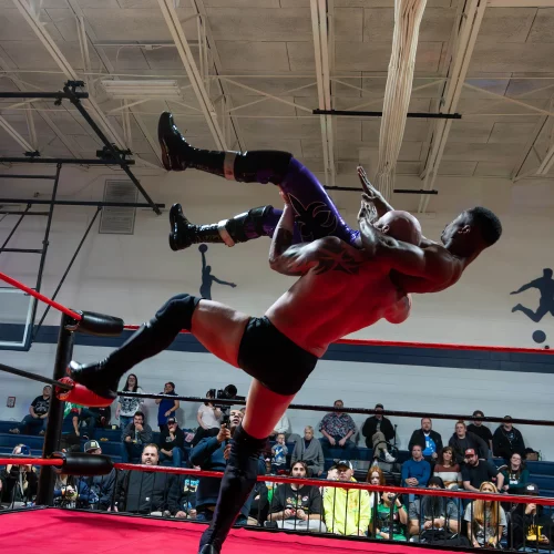 Wrestler throwing his opponent mid-fight during a professional wrestling match captured with sports photography.