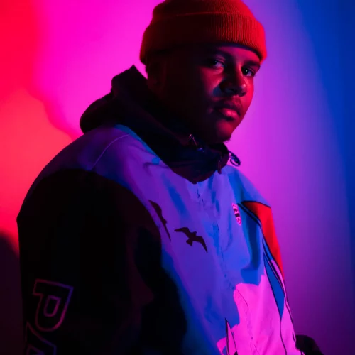 Performer portrait under red and purple stage lighting.