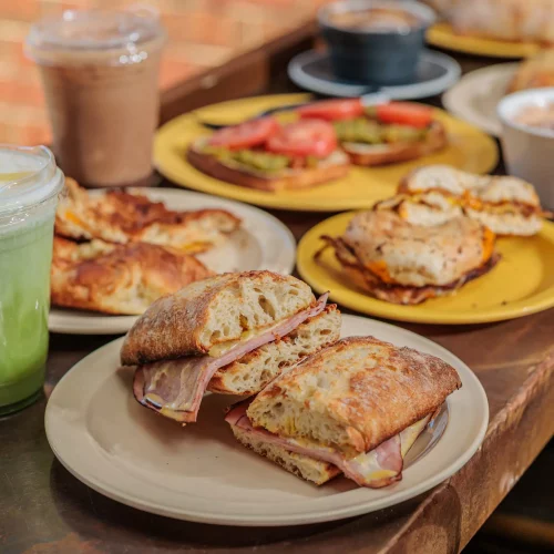 A display of sandwiches spread out on a table with a variety of drinks for customers to enjoy.