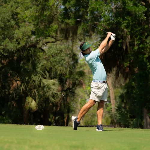 Golfer mid-swing on fairway during a sports branding shoot.