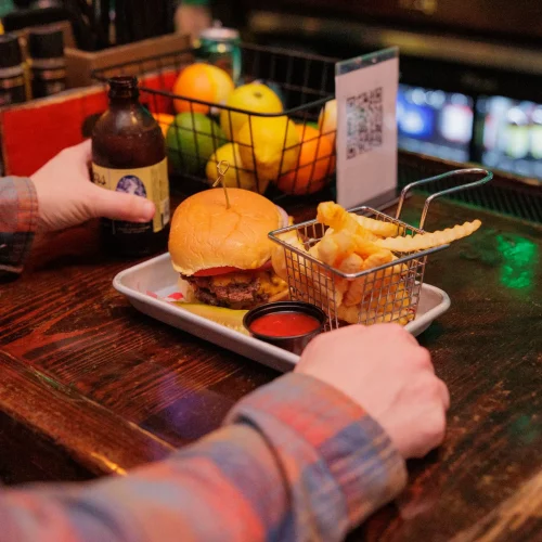 Bartender serving a craft beer to a male customer with a flannel shirt at a Greensboro, NC restaurant bar.