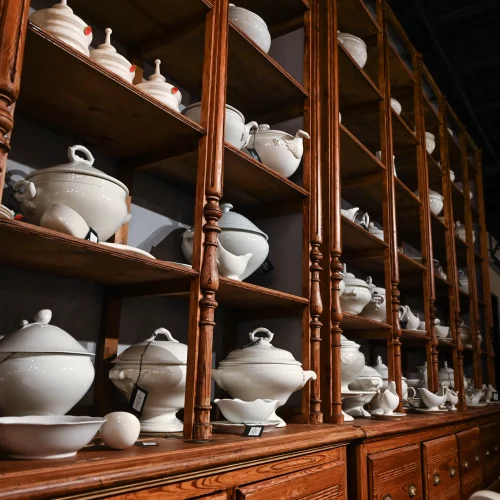 Antique dishware collection displayed on wooden shelving.