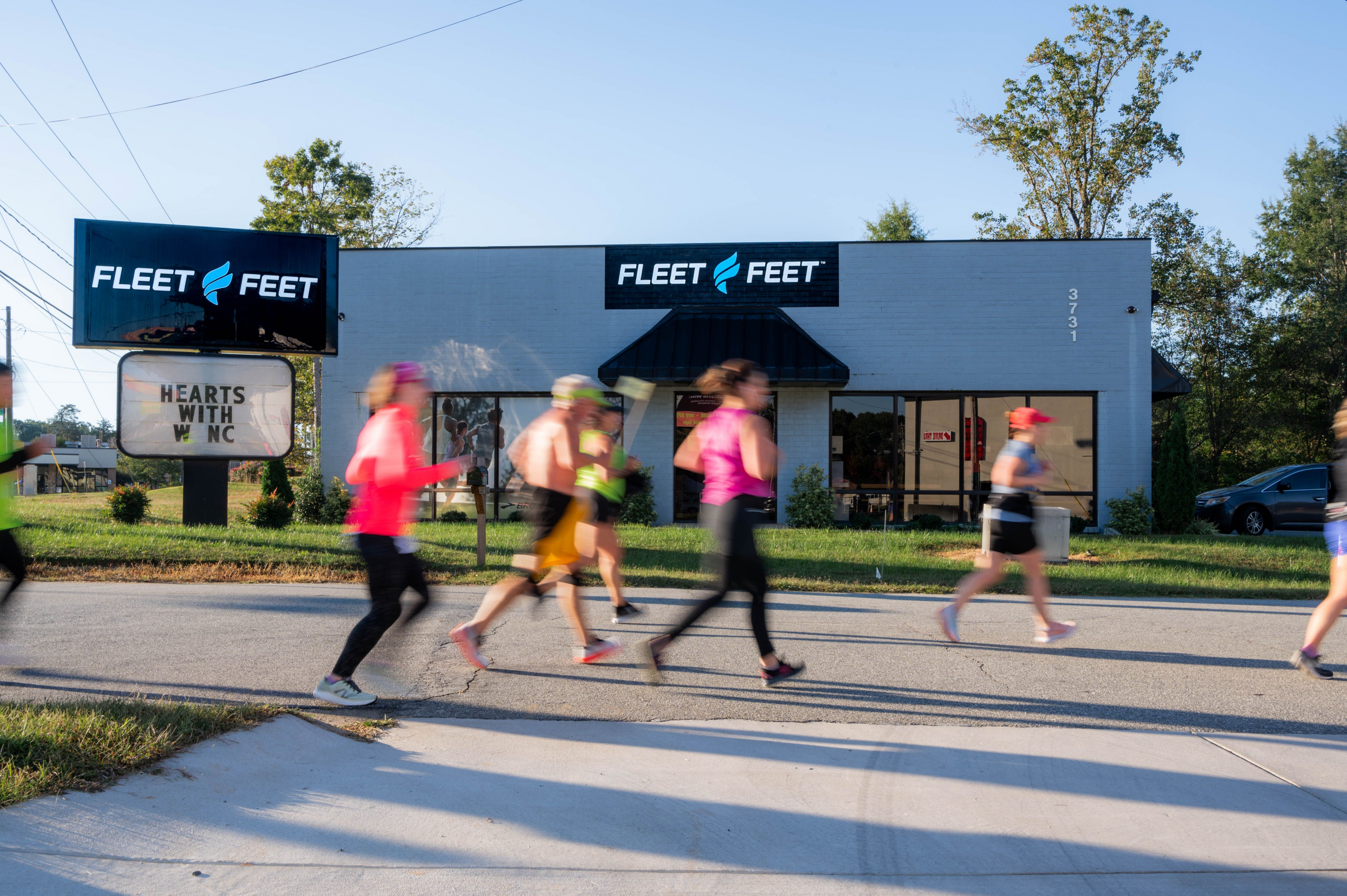 The outside of Fleet Feet in Greensboro as runners go by in a motion blur in North Carolina.