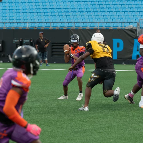 Athletes running plays during youth football tournament with photography coverage by MJS Live Productions.