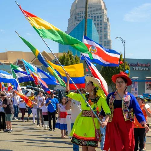 MJS Live Productions capturing dancers in traditional Latin American attire leading a cultural flag parade at the Hispanic League Festival in downtown Winston-Salem, North Carolina