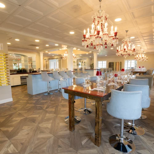 Interior of Rayson Vineyard tasting room in North Carolina, featuring elegant chandeliers, modern bar seating, and wine bottles displayed along the wall.